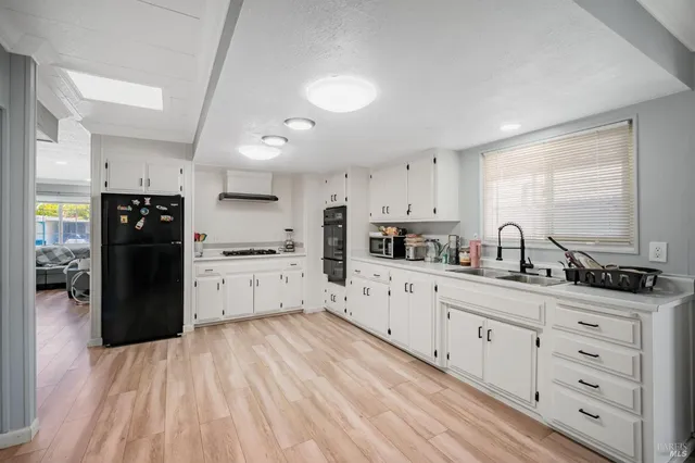 a kitchen with white cabinets and window