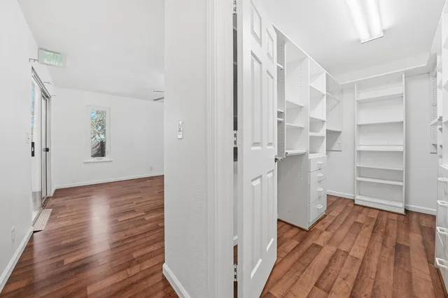 a view of an empty room with window and wooden floor