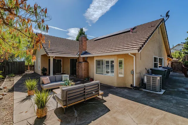a backyard of a house with plants and large tree