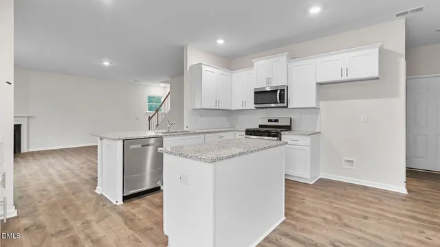 a kitchen with granite countertop a sink and a stove top oven with white cabinets