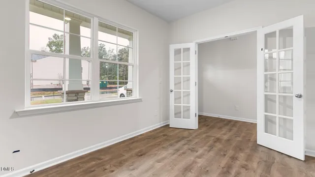 a view of an empty room with wooden floor and windows