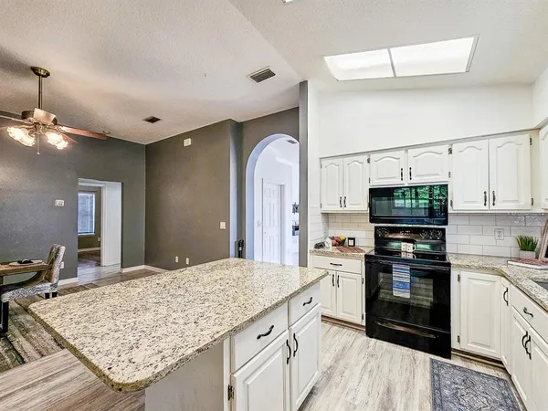 a kitchen with stainless steel appliances granite countertop a stove top oven a sink dishwasher and a refrigerator with wooden floor