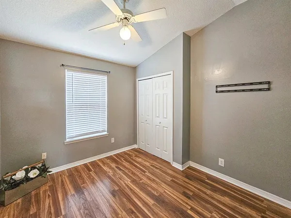 a view of an empty room with a window and wooden floor