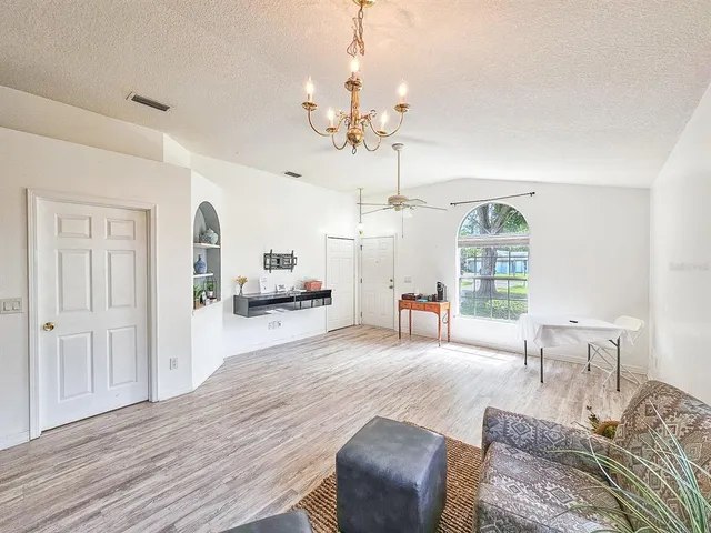 a living room with furniture a chandelier and a window