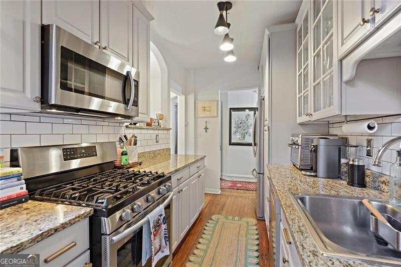 734 Highland Avenue Northeast, Unit 2 Atlanta, GA 30312 - Photo 15 of 24 Kitchen with stainless steel appliances, tasteful backsplash, white cabinets, light wood-style flooring, and glass insert cabinets