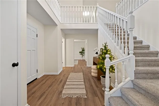 a view of a hallway to a livingroom with wooden floor and stairs