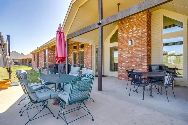 a patio with a table and chairs and potted plants