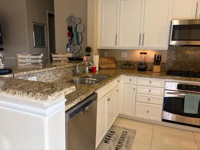 a kitchen with granite countertop a sink stainless steel appliances and cabinets