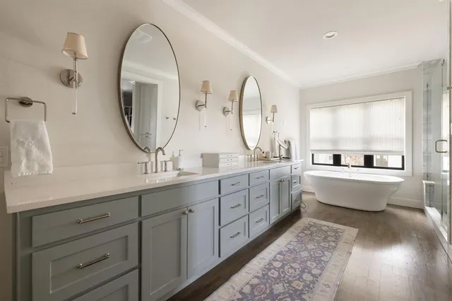 a large bathroom with double vanity sinks a two mirror a window a bathtub and a vanity