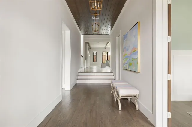a view of a hallway with wooden floor and a dining room