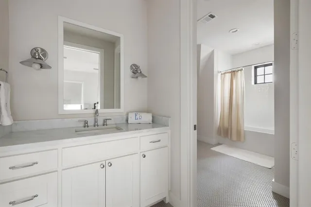 a en suite bathroom with a granite countertop sink and a mirror