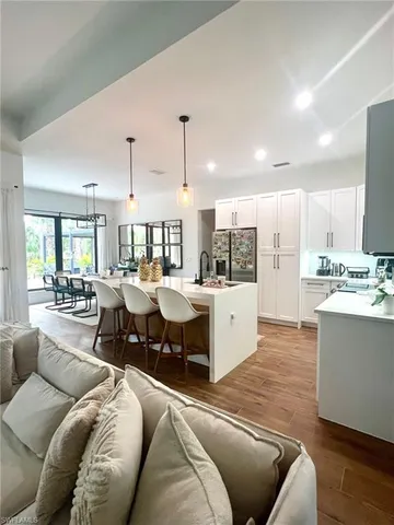 a kitchen with stainless steel appliances kitchen island granite countertop a table chairs and a refrigerator