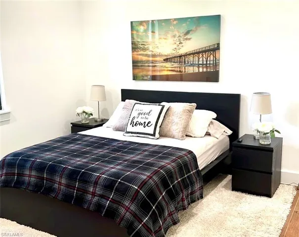 a bedroom with a bed a dresser with wooden floor