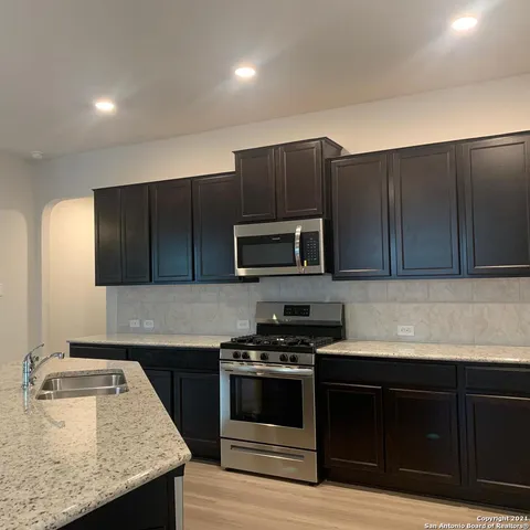 a kitchen with kitchen island granite countertop stainless steel appliances wooden cabinets and a sink
