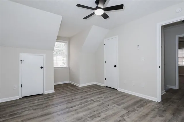 an empty room with wooden floor closet and windows