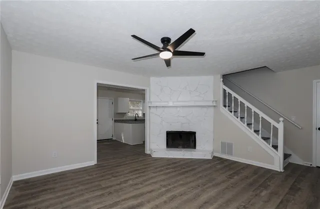 a view of an empty room with wooden floor and a kitchen