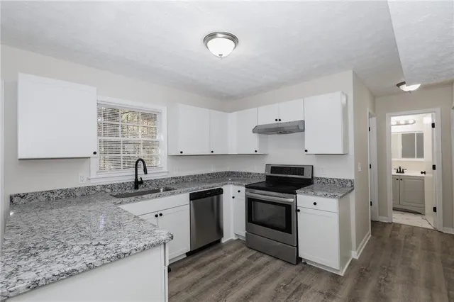 a kitchen with stainless steel appliances granite countertop a sink stove and cabinets