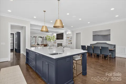 a kitchen with kitchen island a sink a stove a dining table and chairs