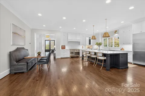 a living room with furniture and kitchen view with wooden floor