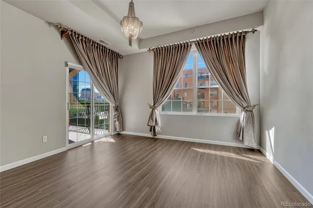 an empty room with wooden floor staircase and windows