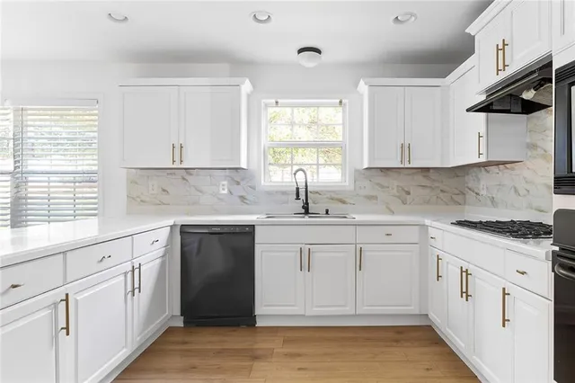 a kitchen with white cabinets appliances a sink and a window