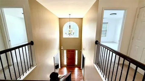 a view of a hallway with wooden floor and stairs