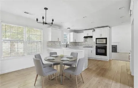 a kitchen with kitchen island a dining table chairs and white cabinets