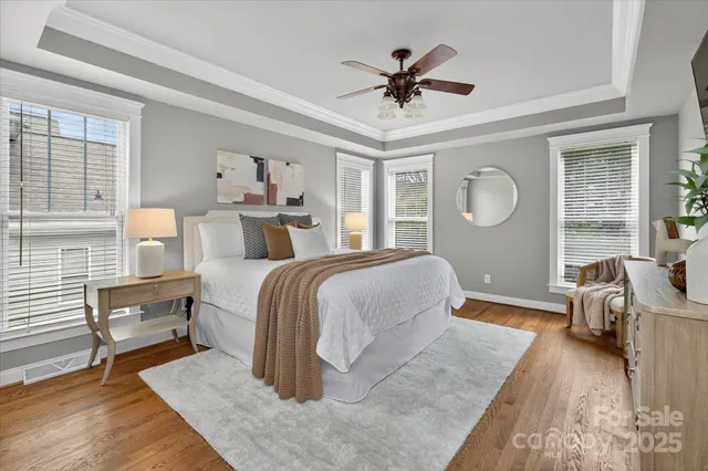 a bedroom with a large bed a chandelier and windows