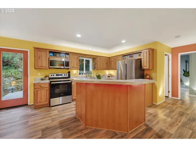 a kitchen with stainless steel appliances granite countertop a stove top oven a sink dishwasher and wooden cabinets with wooden floor