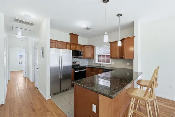 a kitchen with stainless steel appliances granite countertop a refrigerator a stove and a wooden floor