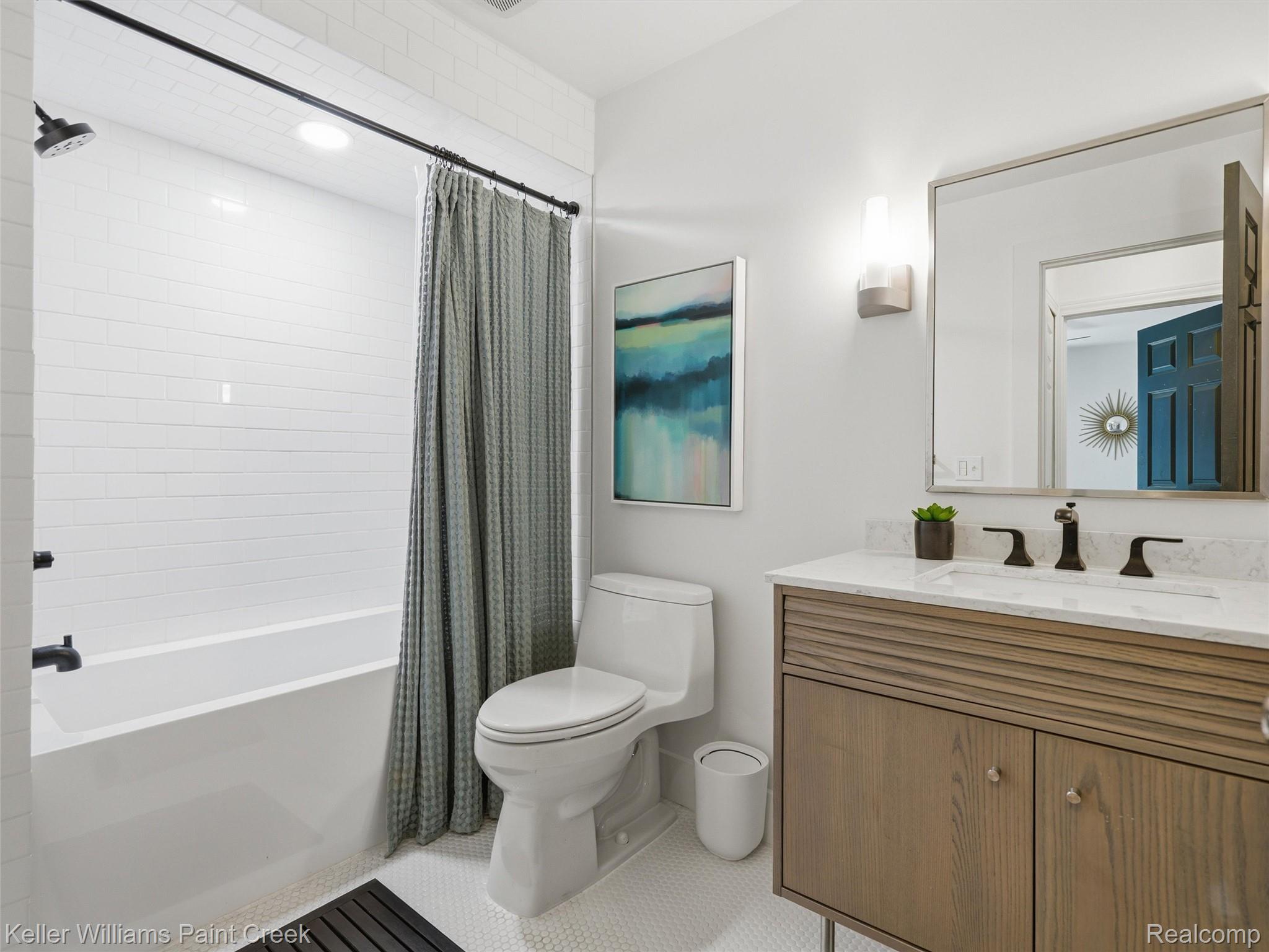 10435 Spring Street Fenton, MI 48430 - Photo 21 of 40 Full bathroom featuring a white subway tile tub surround, white hex tile flooring, and a single vanity with a light wood-finish cabinet and white countertop