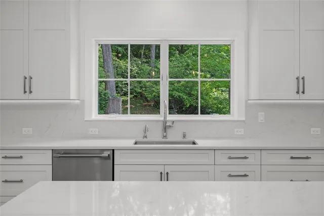 a kitchen with granite countertop white cabinets and a window