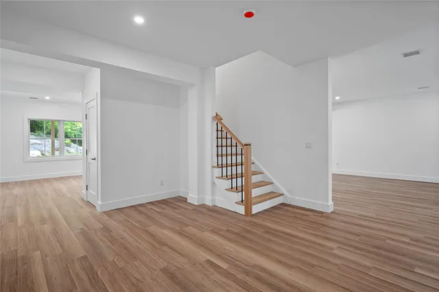 an empty room with wooden floor entryway and windows