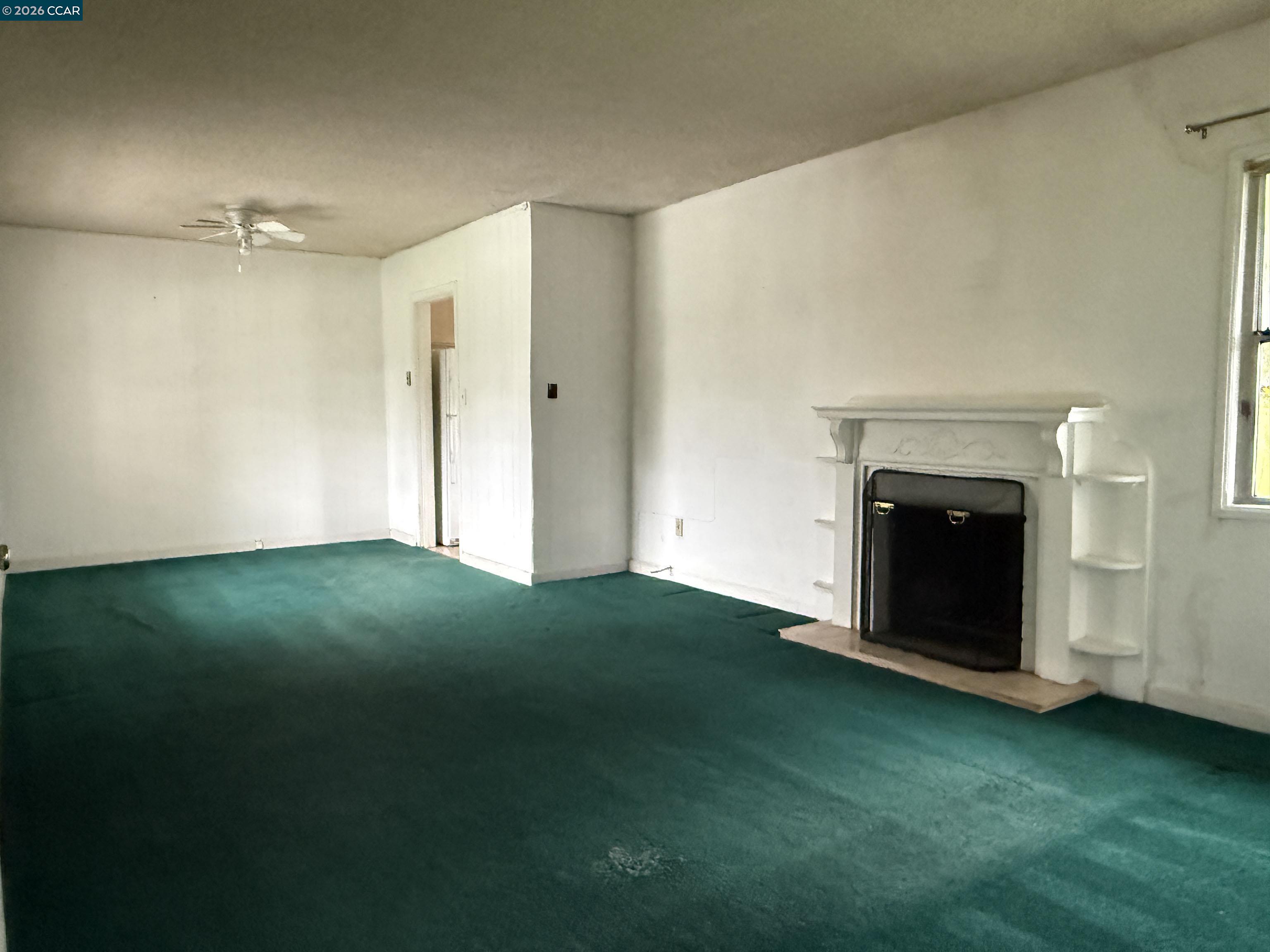 a view of an empty room with a fireplace and a window