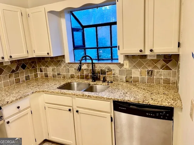 a kitchen with stainless steel appliances granite countertop white cabinets sink and a granite counter top