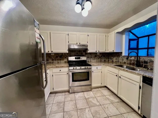a kitchen with a refrigerator sink and cabinets
