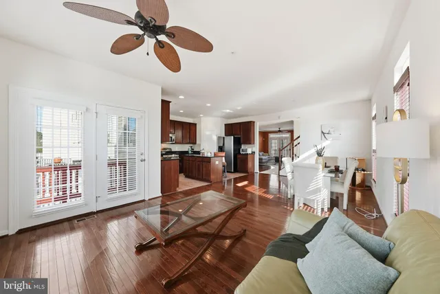 a living room with furniture kitchen view and a wooden floor