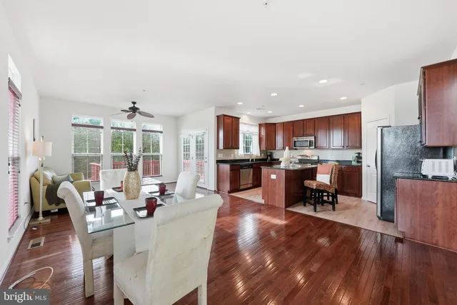 a living room with dining table furniture wooden floor and a kitchen view