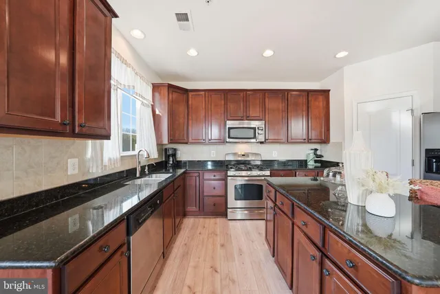 a kitchen with kitchen island granite countertop a sink stove and cabinets