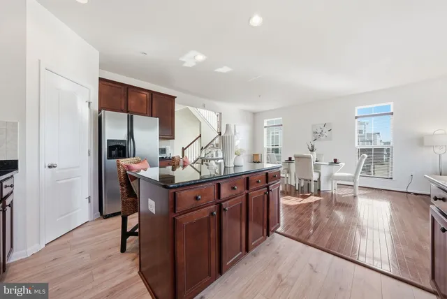 a view of kitchen island with stainless steel appliances granite countertop sink and wooden floor