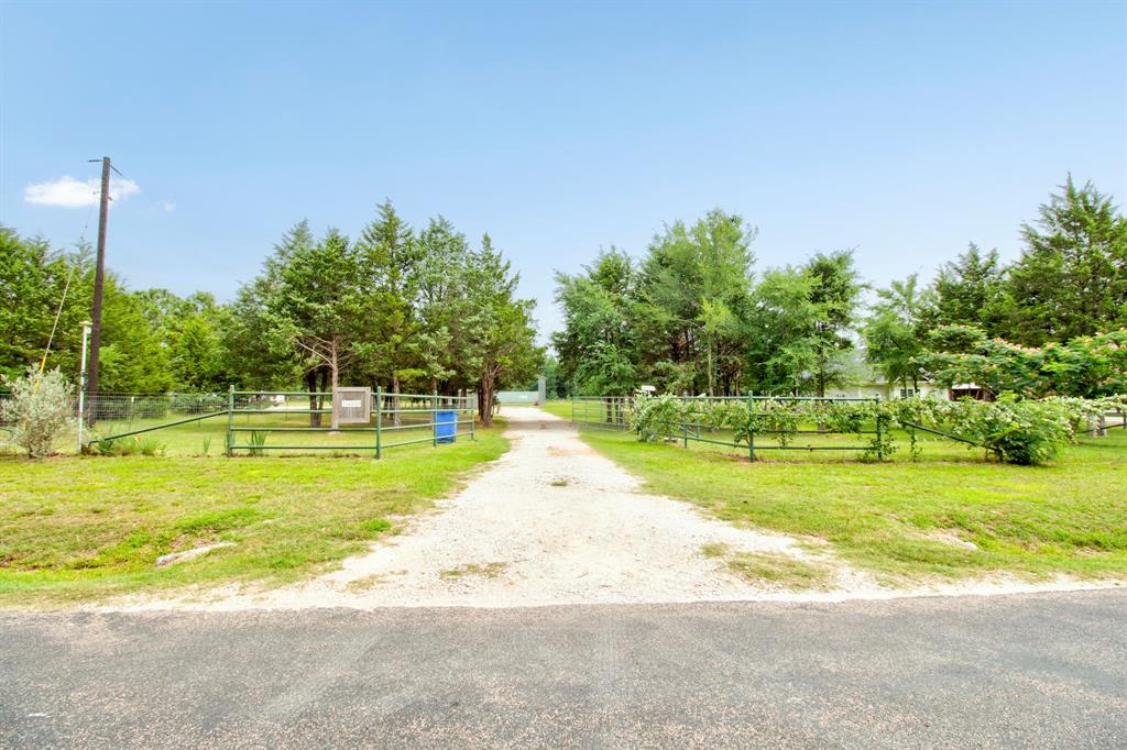 Gravel driveway entrance with wire fencing and established trees
