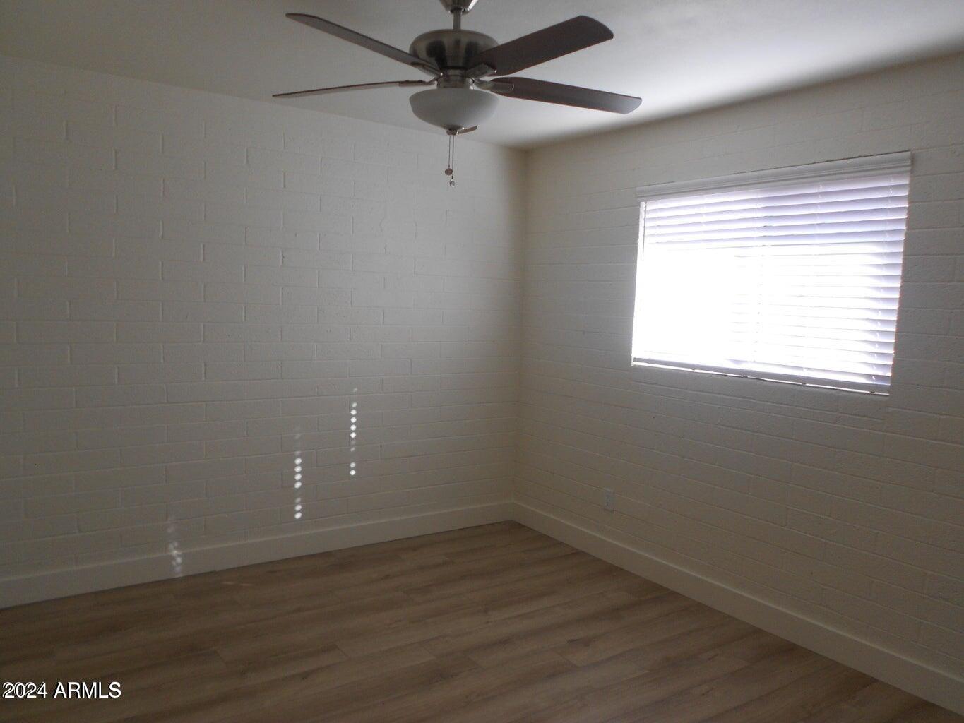 3151 North 36th Street, Unit 5 Phoenix, AZ 85018 - Photo 8 of 13 an empty room with wooden floor fan and windows