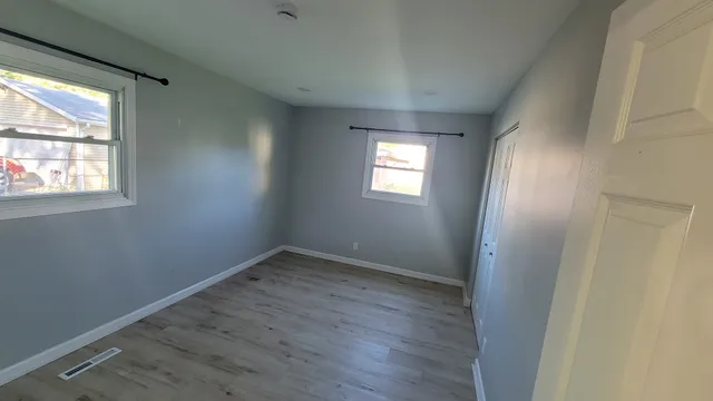 an empty room with wooden floor and windows