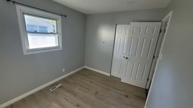 a view of an empty room with wooden floor and a window
