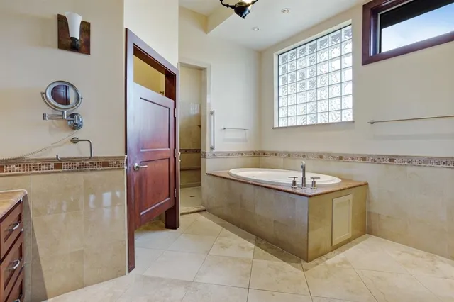 a spacious bedroom with a bed and a lamp on the dresser