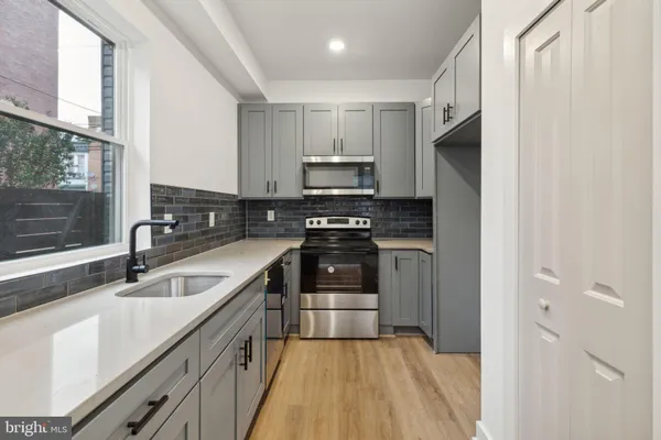 a kitchen with granite countertop a refrigerator sink and white cabinets