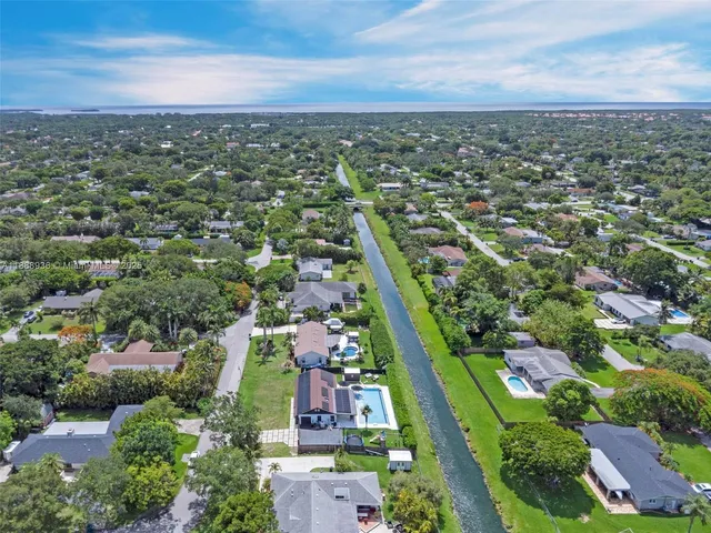 an aerial view of residential houses with outdoor space and trees