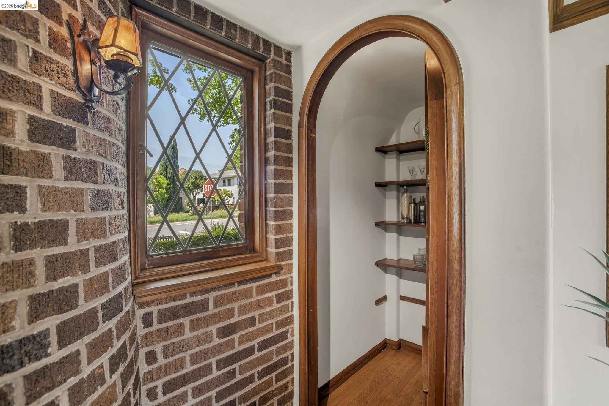 1087 Hubert Road Oakland, CA 94610 - Photo 6 of 67 Curved brick wall with a leaded glass window, featuring an attached sconce light fixture