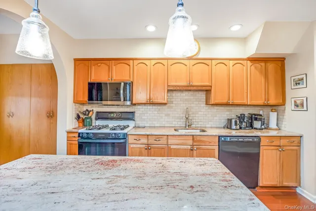 a kitchen with stainless steel appliances granite countertop a sink a stove cabinets and wooden floor