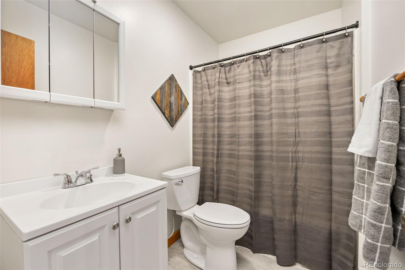 9380 West 49th Avenue, Unit 101 Wheat Ridge, CO 80033 - Photo 7 of 15 a bathroom with a sink a toilet and shower curtain